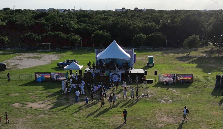 Aerial view of a small outdoor concert with a stage, tent, and audience.