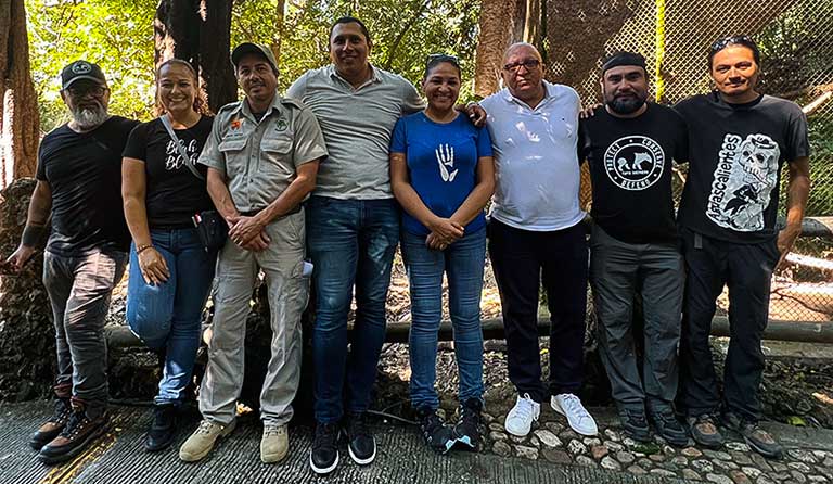 Seven people standing in a line outdoors, smiling at the camera.