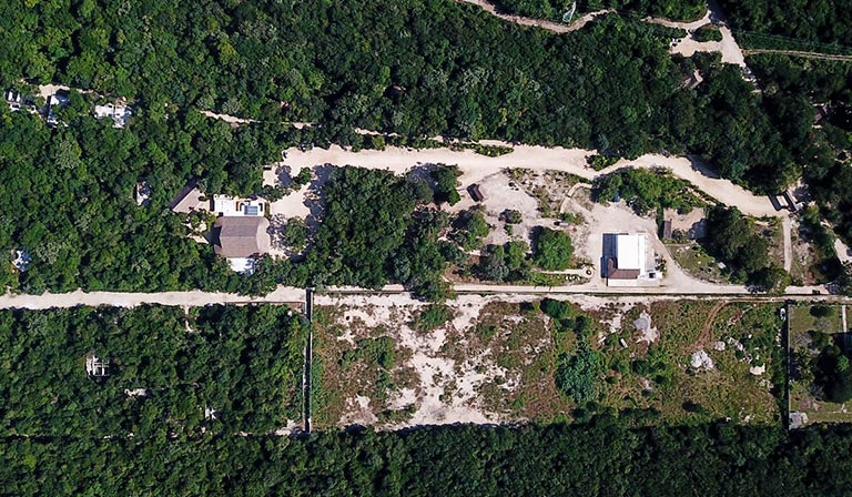 Aerial view of a forested area with scattered buildings and dirt roads.