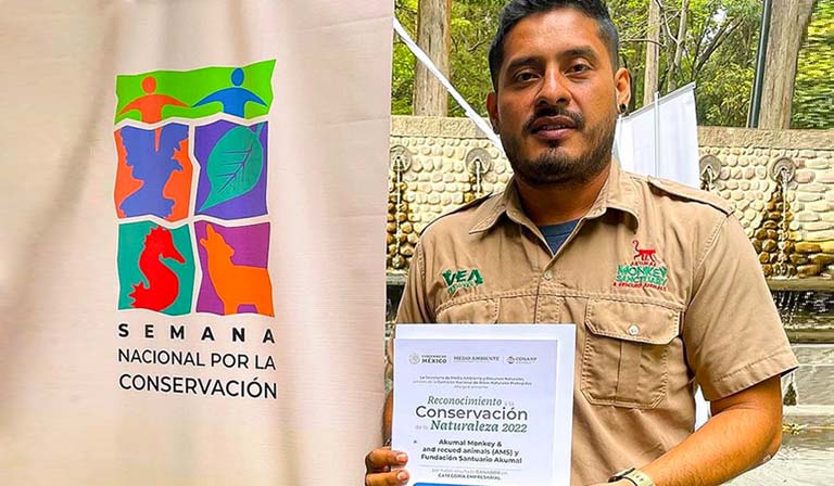Man holding a certificate beside a conservation banner outdoors.