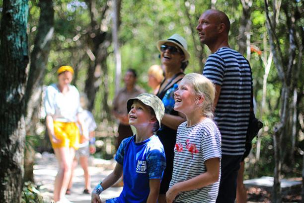 Family with children smiling and looking up in a forest.